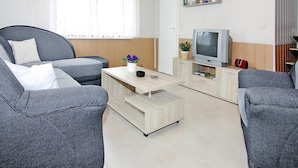 Een moderne woonkamer met een bank, salontafel, televisie en boekenkast.