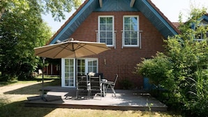 Een huis met een bakstenen gevel, een puntig dak en een patio met tuinmeubilair.