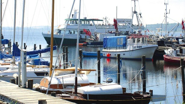 Een jachthaven met verschillende boten afgemeerd, waaronder een witte boot met de tekst 'REER 28' op de zijkant.