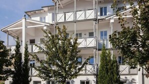 Un immeuble résidentiel à plusieurs étages, doté de balcons et d’un espace extérieur couvert.