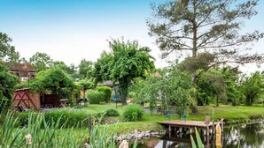 Un jardin paisible avec un étang, une jetée en bois et un petit abri de jardin.
