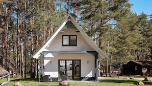 A cabin with a triangular roof, a front porch, and a large window. - Doppelhaushalften im Naturresort Drewitz (Nossentiner Huette)