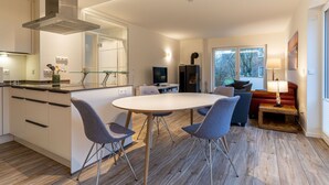 A modern kitchen with a central island, dining chairs, a sofa, a TV, and a fireplace. - Doppelhaushalfte, St. Peter-ording (St. Peter-Ording)