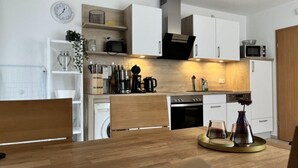 A modern kitchen with white cabinets, a wooden countertop, and a dining table with chairs. - Apartment in Trassenheide for 4 Personen (Trassenheide)