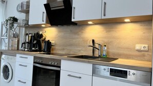 A modern kitchen with a dishwasher, oven, sink, and coffee maker. - Apartment in Trassenheide for 4 Personen (Trassenheide)