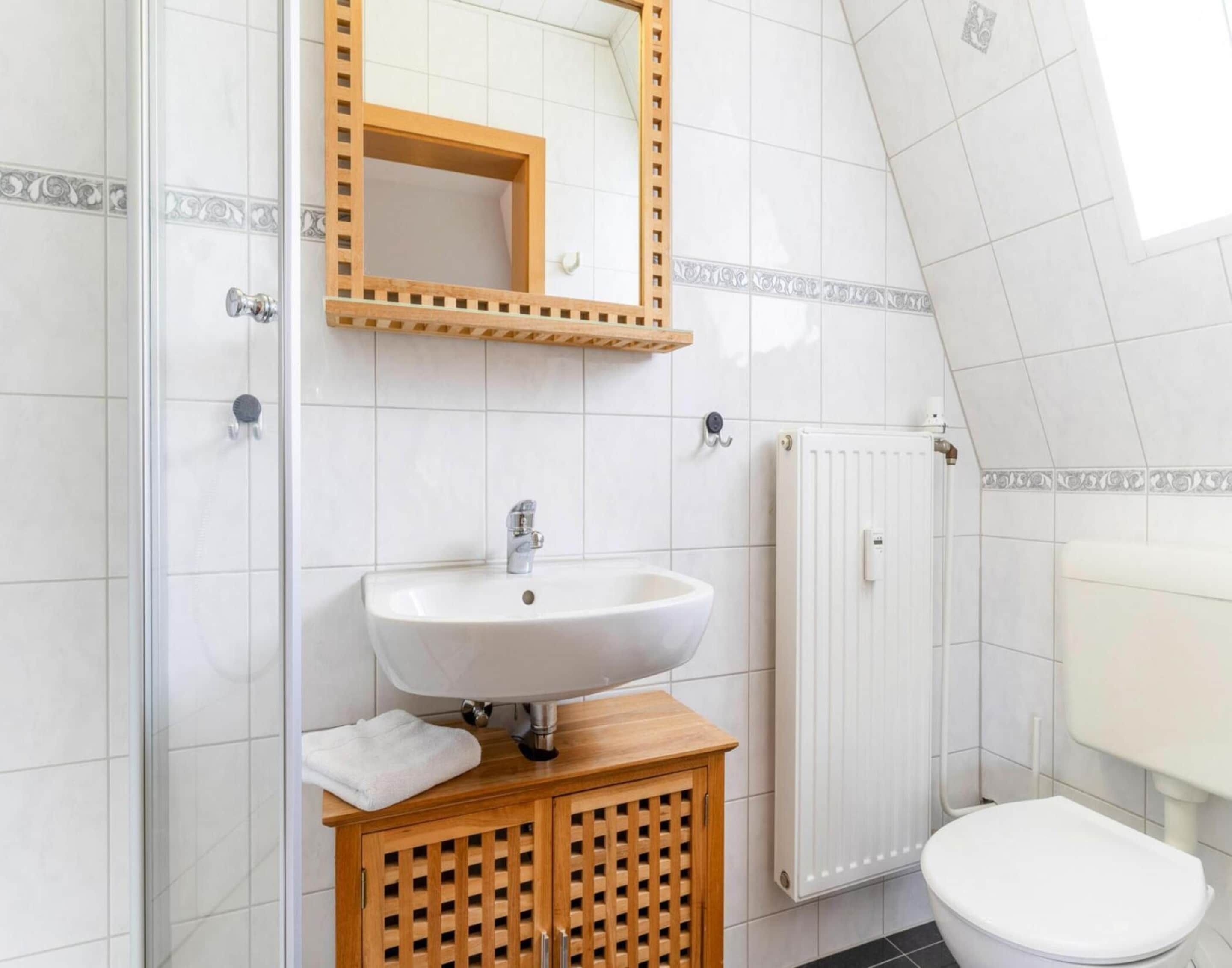 A bathroom with a white sink, wooden cabinet, and a toilet.