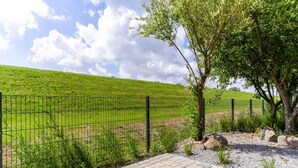 Un vialetto lastricato conduce a un'area recintata con un prato e un albero sullo sfondo.