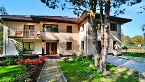 A two-story house with a balcony, a paved driveway, and a well-maintained garden. - Villa in Mielno Near Seaside Beach (Mielno)