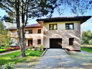 Stylish two-story home with a flat roof, garage, and beautifully maintained garden.