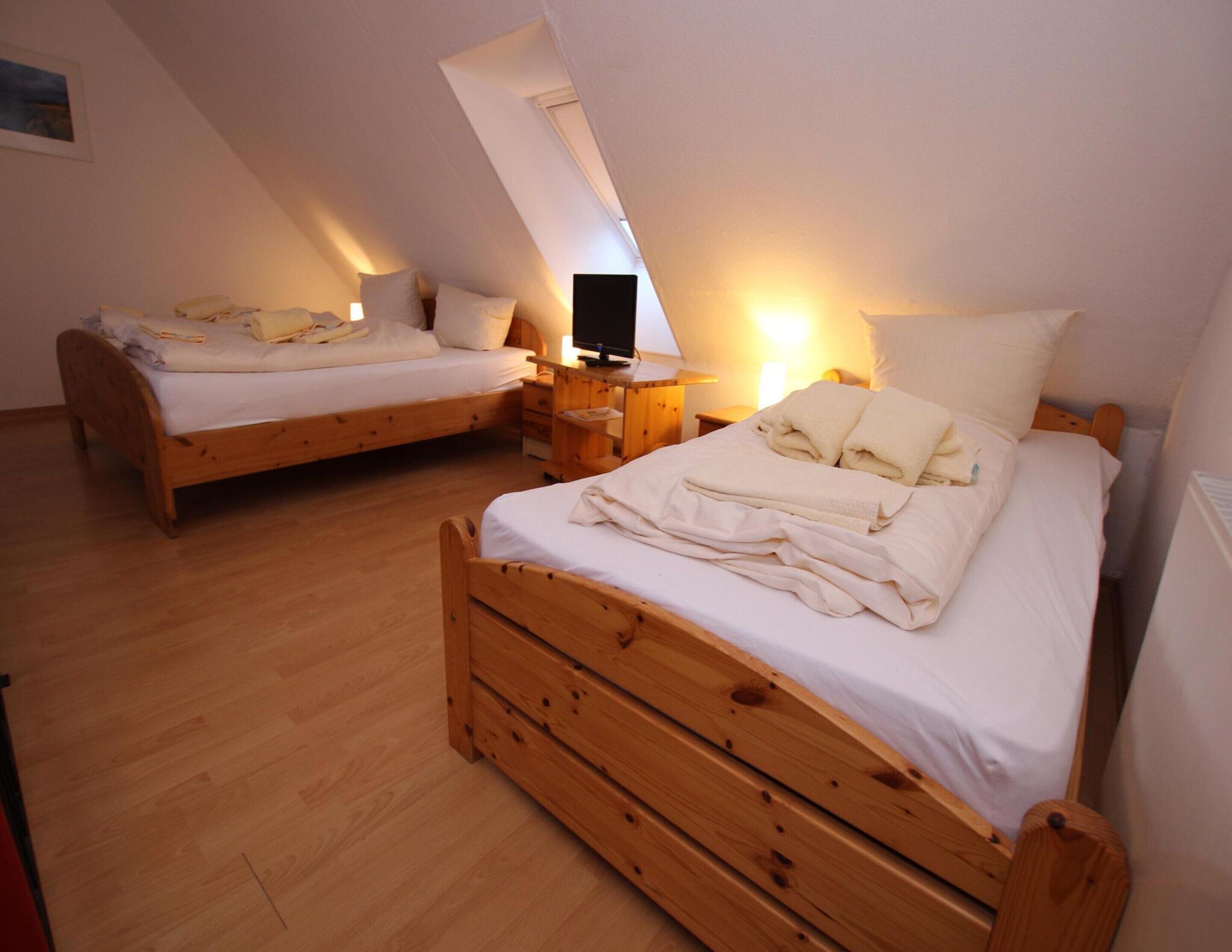 A bedroom with two wooden beds, each with a nightstand and a lamp.