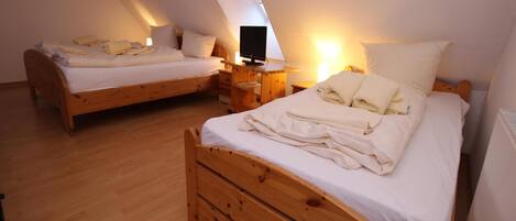 A bedroom with two wooden beds, each with a nightstand and a lamp.