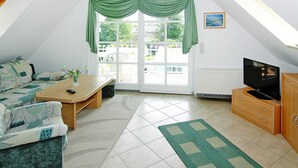 A cozy living room with a sofa, coffee table, and TV stand. - Charmante Ferienwohnung auf Rugen, Altenkirchen (Altenkirchen)