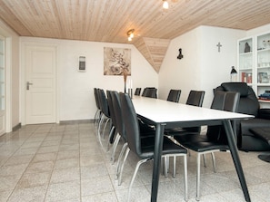 A conference room with a long table and chairs, a white door, and a bookshelf with books and decorative items. - 4 Star Holiday Home in Ulfborg (Ulfborg)