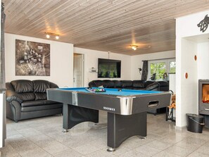 A pool table in a room with a wooden ceiling, a black leather sofa, and a fireplace. - 4 Star Holiday Home in Ulfborg (Ulfborg)