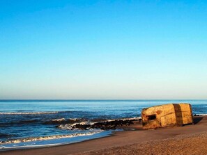 En strand med en stor, väderbiten betongkonstruktion vid strandkanten.
