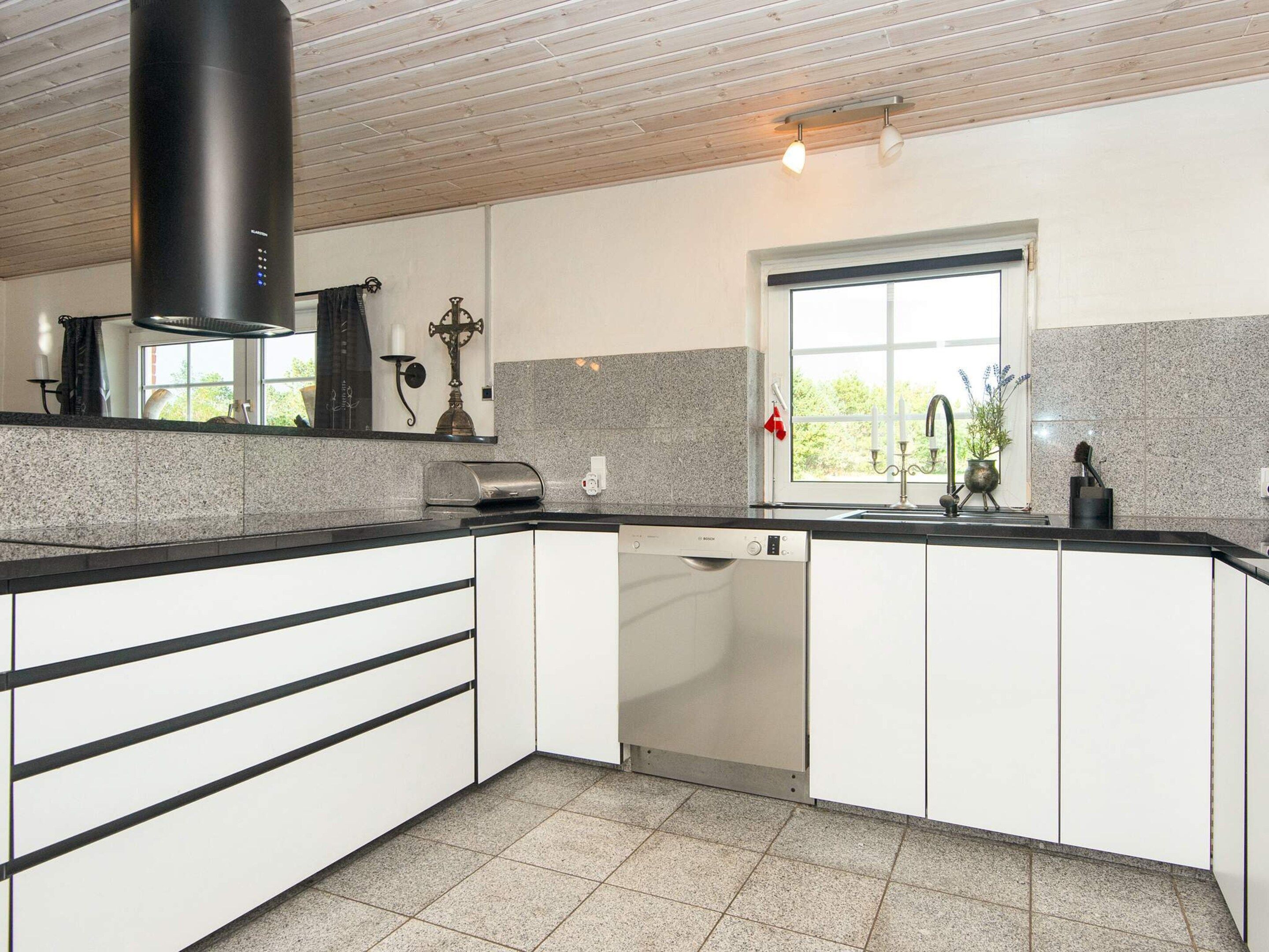 A modern kitchen with a Bosch dishwasher, a window with a view, and a wooden ceiling.