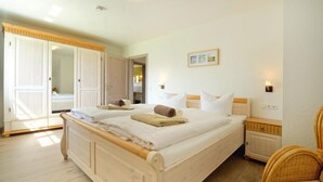Une chambre à coucher avec un lit en bois, une armoire, une chaise et une table de chevet.