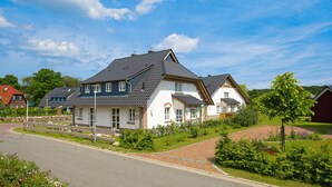 Un quartier résidentiel avec des maisons modernes, une allée pavée et des jardins bien entretenus.