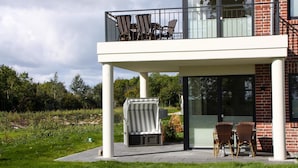 A modern building with a balcony, outdoor seating, and a glass door entrance. - Ferienwohnung auf Fehmarn for 2 Personen (Fehmarn)