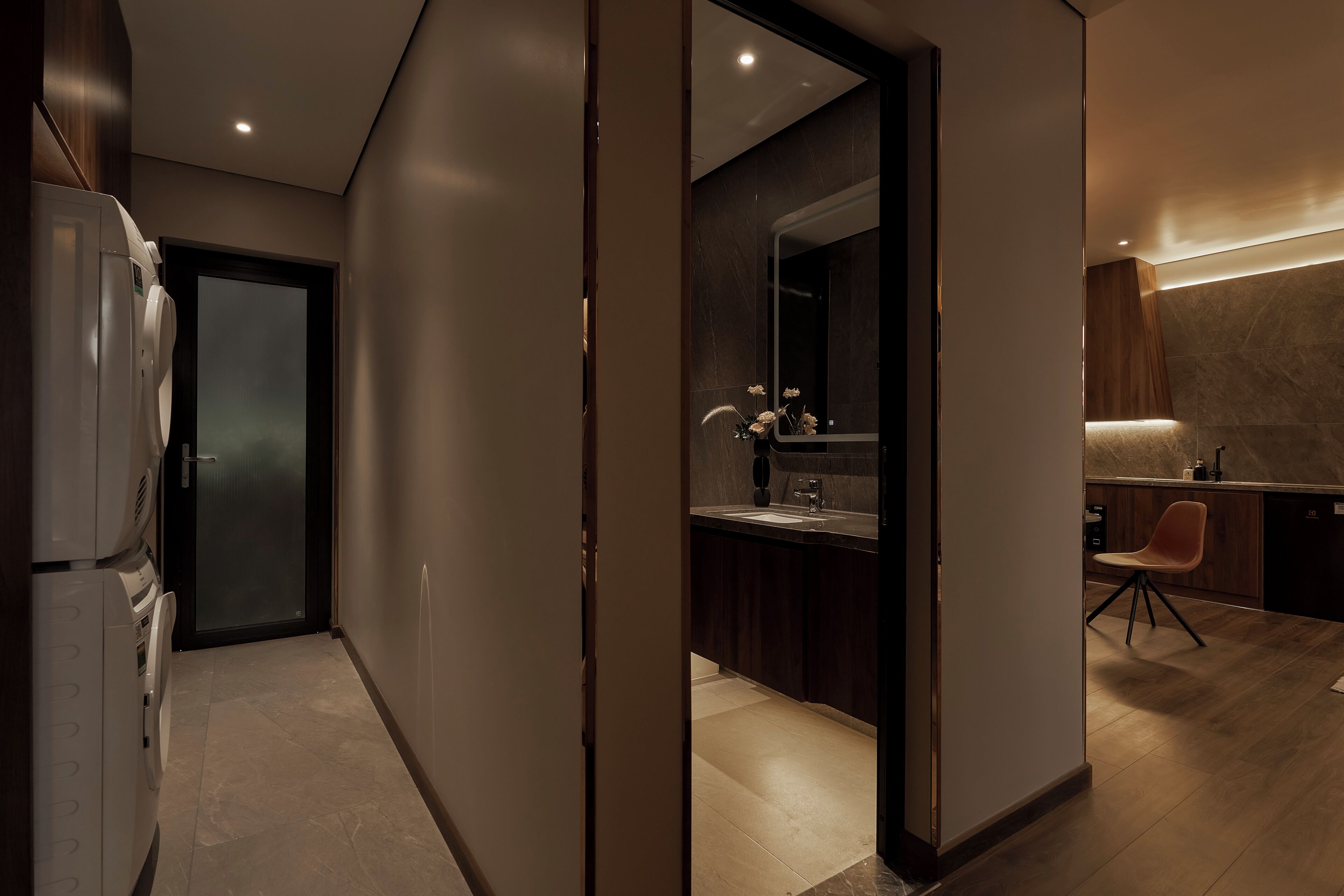 A modern kitchen with a dark countertop, a sink, and a chair.