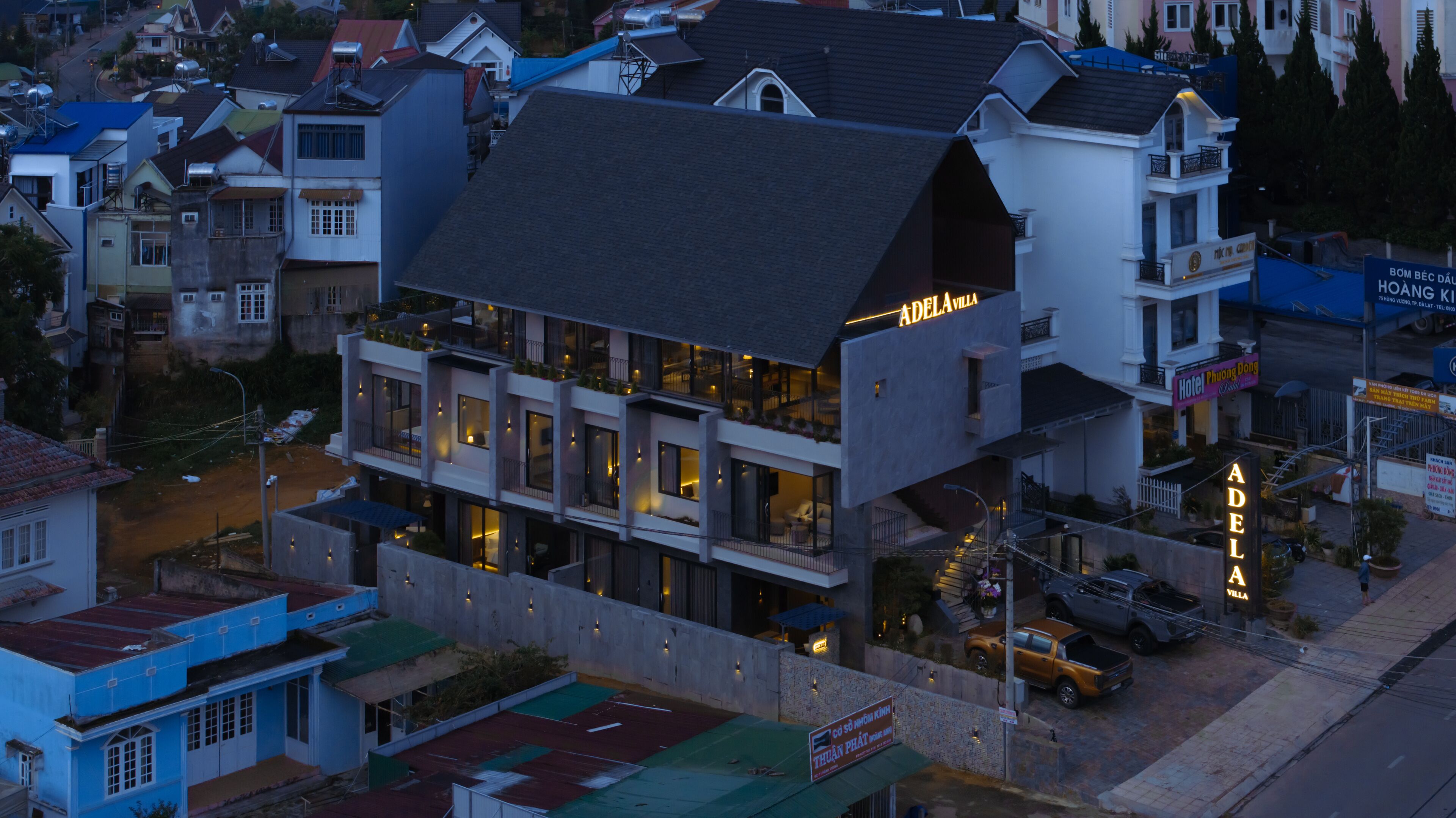 A multi-story hotel with a prominent 'ADELAVILLA' sign, featuring balconies and a modern architectural design.