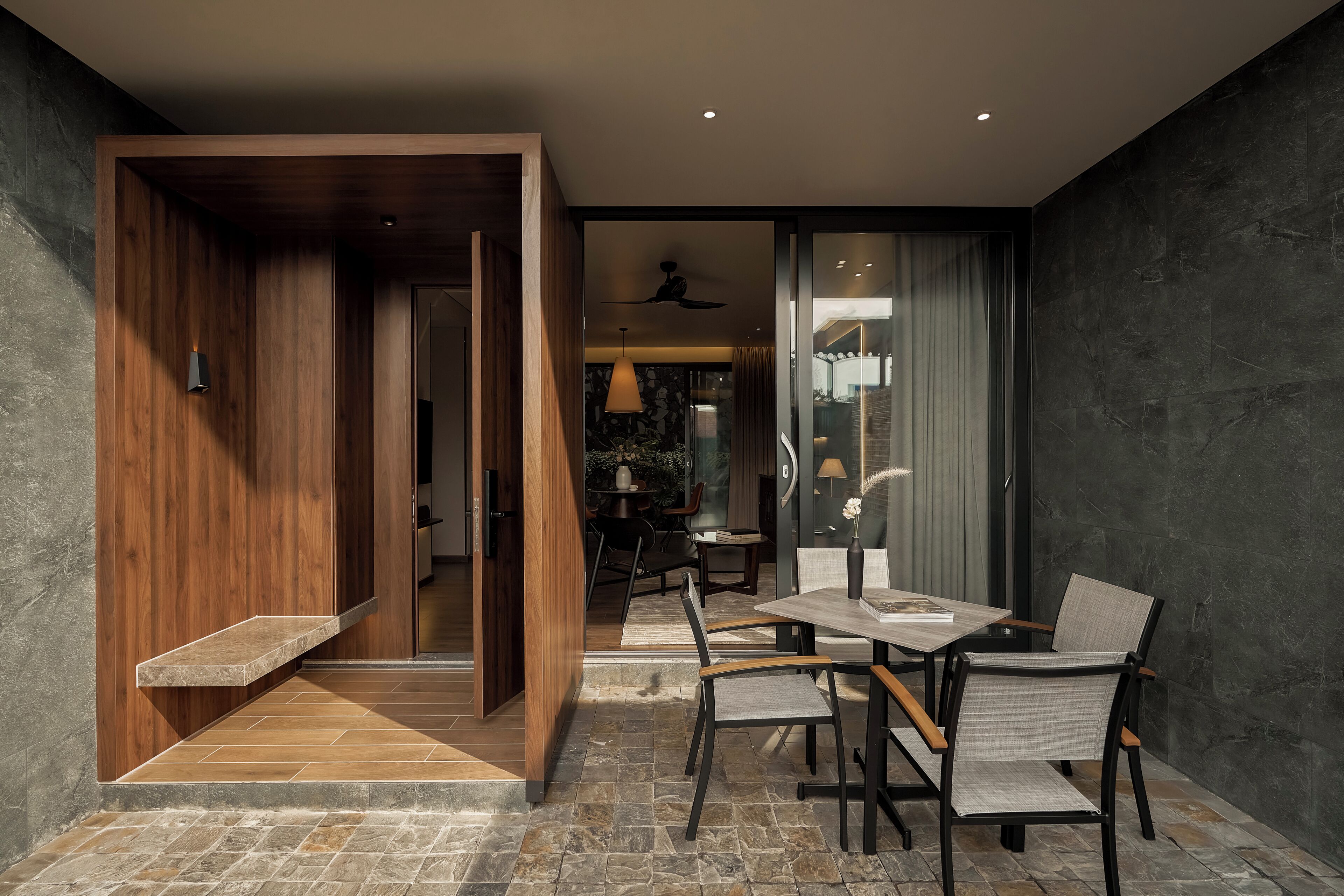 A modern dining area with a wooden accent wall, a stone-tiled floor, and a table with four chairs.
