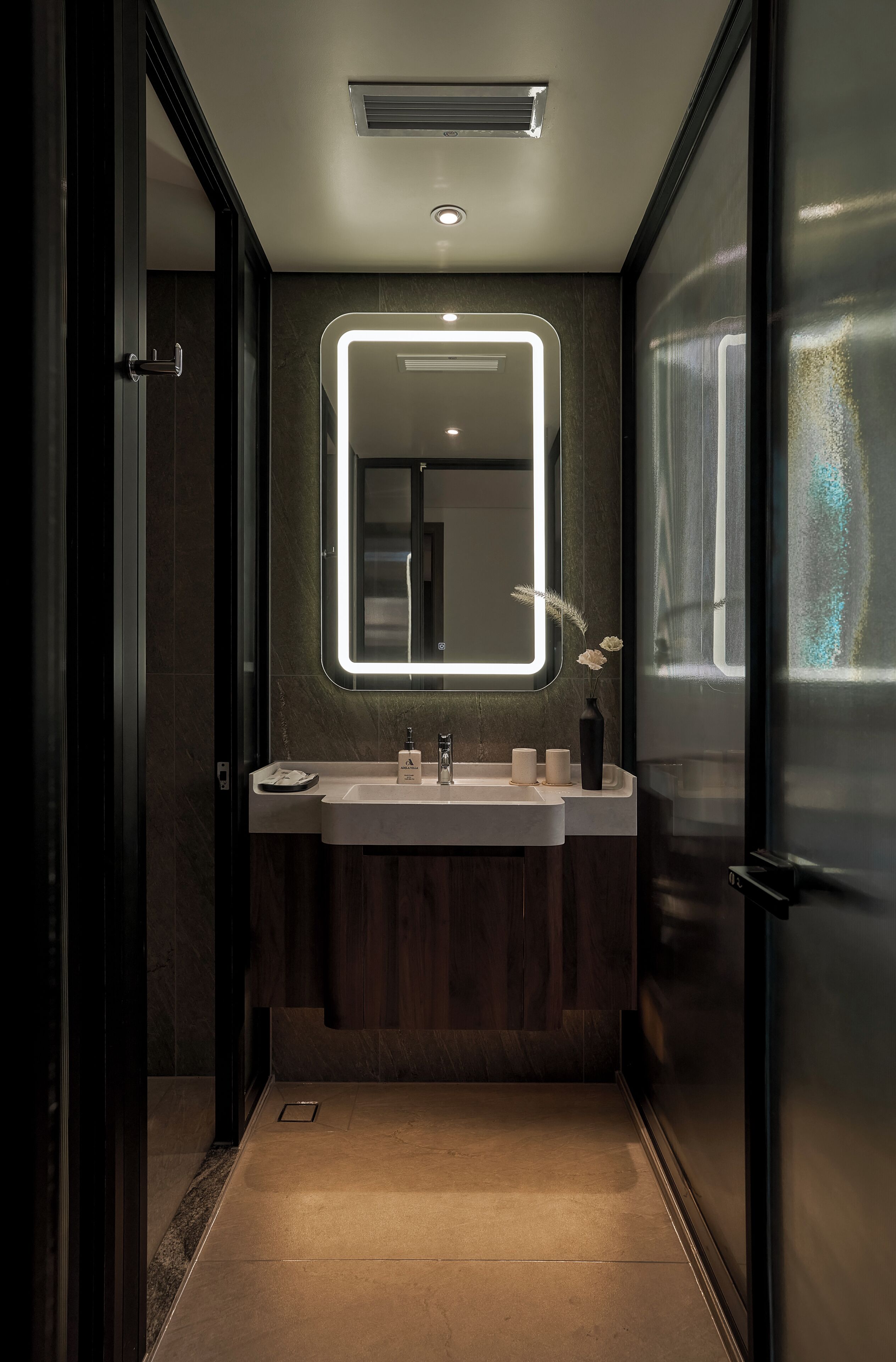 A modern bathroom with a rectangular mirror, a sink, and a vase with flowers.
