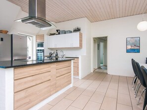 A modern kitchen with a central island, stainless steel appliances, and a wooden cabinet.