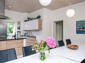 A modern kitchen with white cabinets, a wooden countertop, and a dining area with a white table and chairs.
