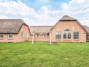 A traditional brick building with a thatched roof, a swing set, and a well-maintained lawn.