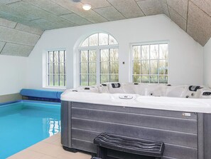 A hot tub with a view of a swimming pool and large windows. - 4 Star Holiday Home in Ulfborg (Ulfborg)