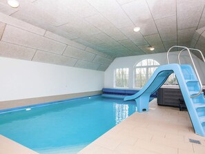 An indoor swimming pool with a blue slide, tiled walls, and a bench along the wall. - 4 Star Holiday Home in Ulfborg (Ulfborg)