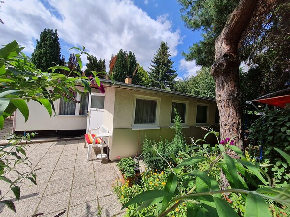 Una casa con un patio, una silla blanca y una planta en maceta.
