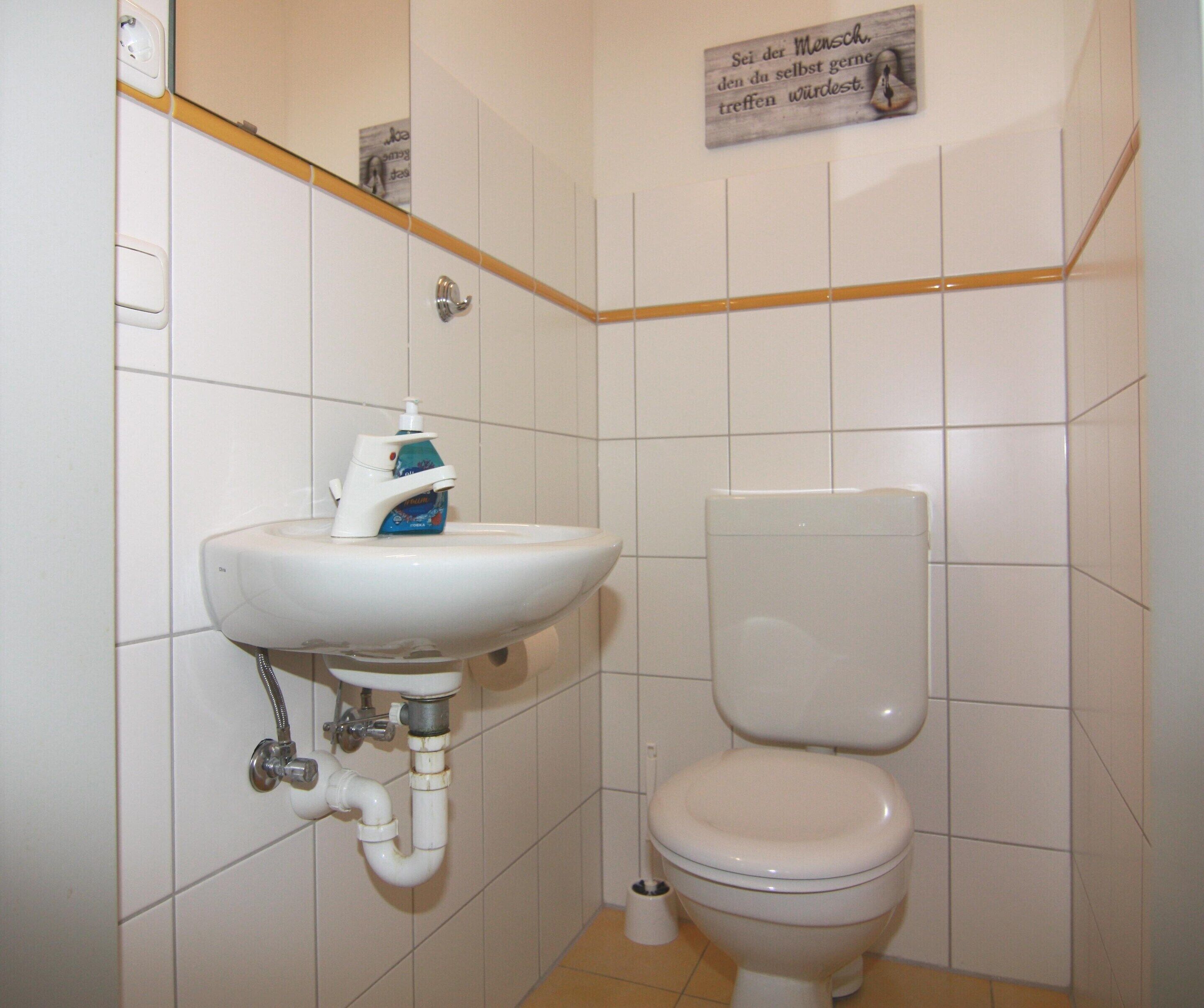 A small bathroom with a white sink, toilet, and a hand dryer.