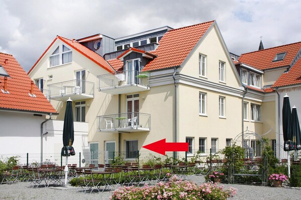 A multi-story building with a red-tiled roof, balconies, and outdoor seating. - Ferienwohnung Grosser Seestern in Wiek (Wiek)