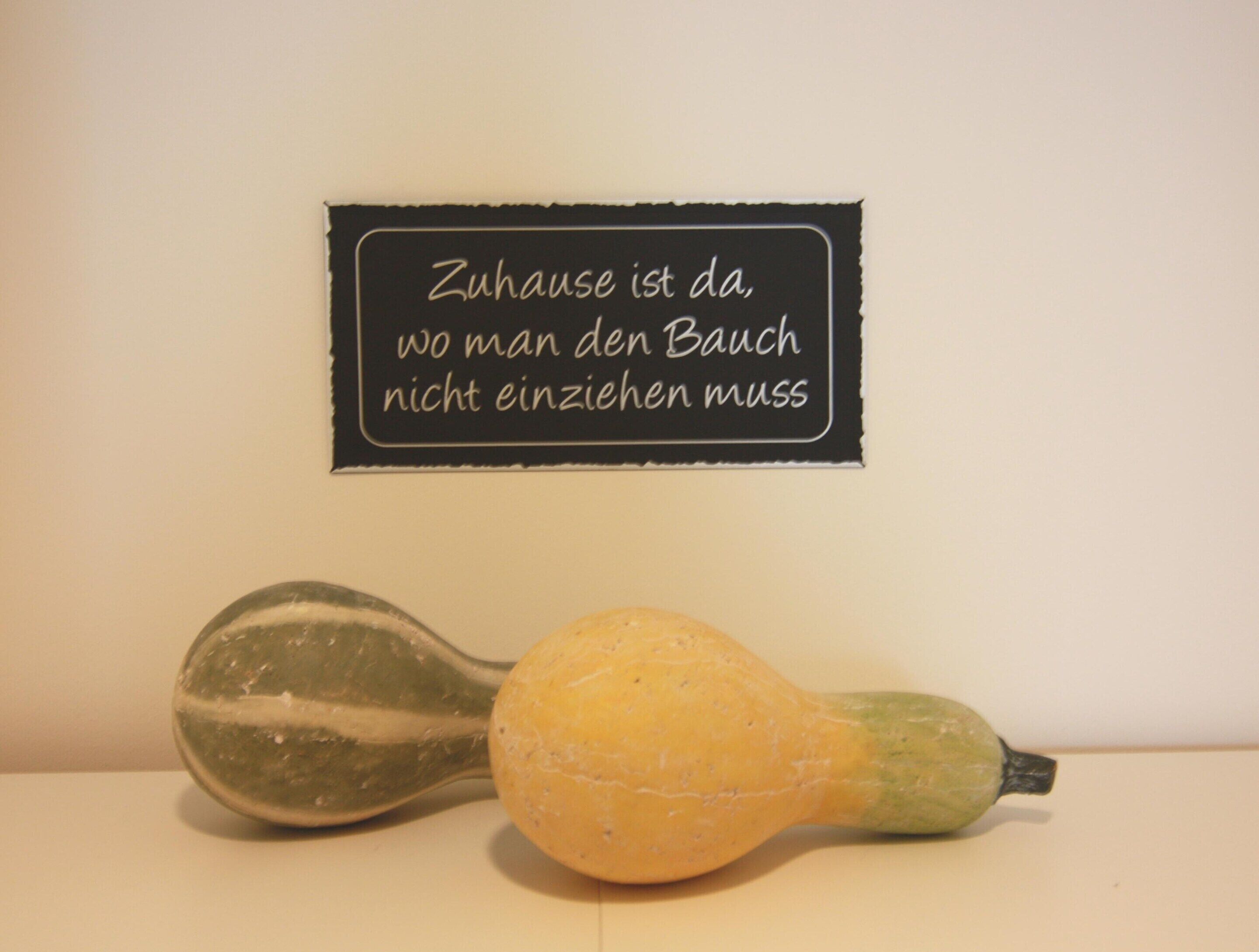 Une pancarte avec un message en allemand et deux courges sur une table.