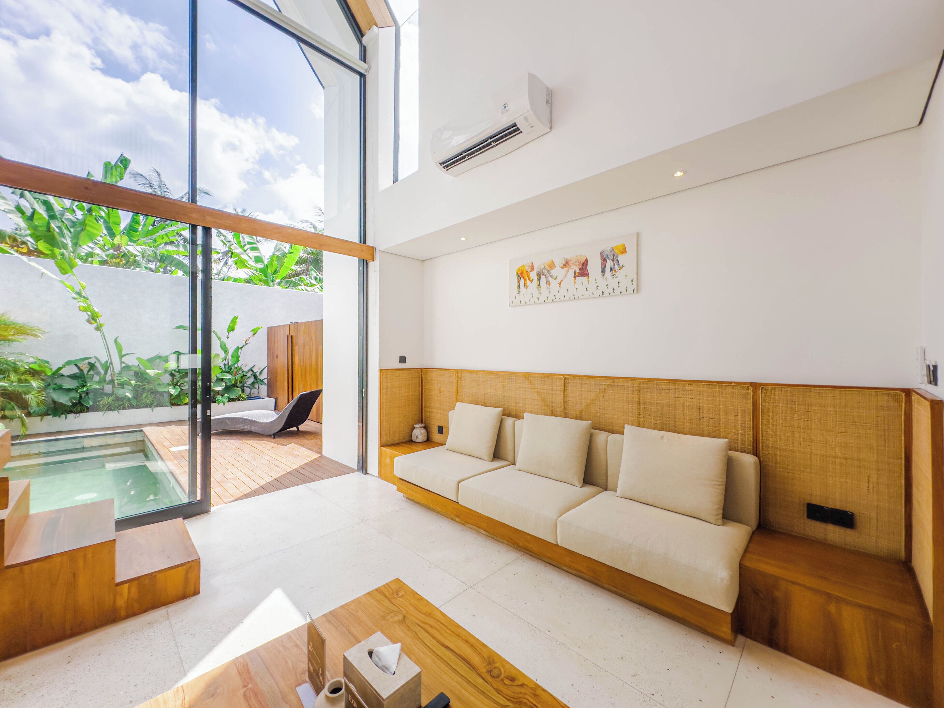 Uma sala de estar moderna com uma grande janela, um sofá, uma mesa de centro e uma pequena área de piscina.