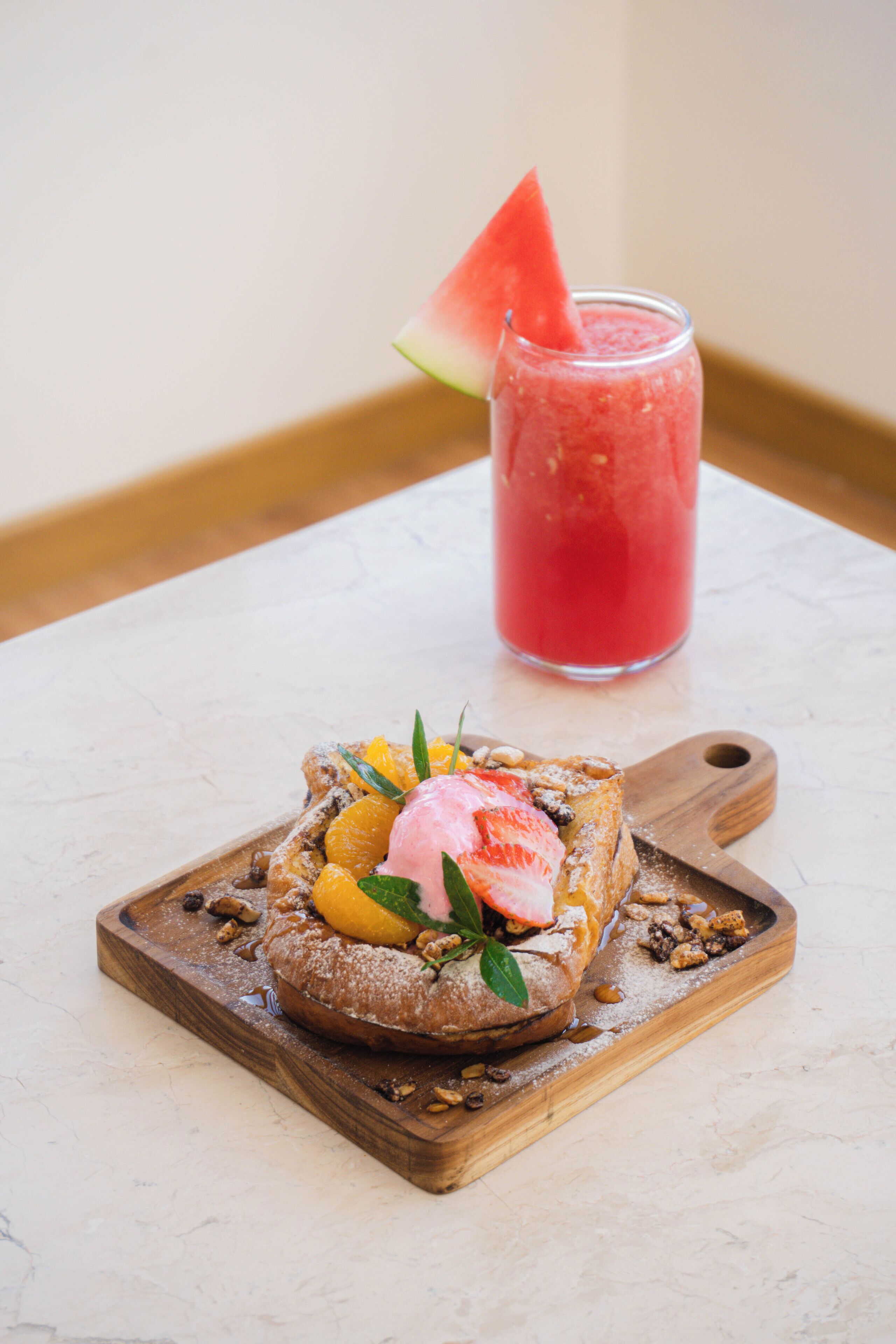 A dessert on a wooden board with a glass of red beverage in the background.