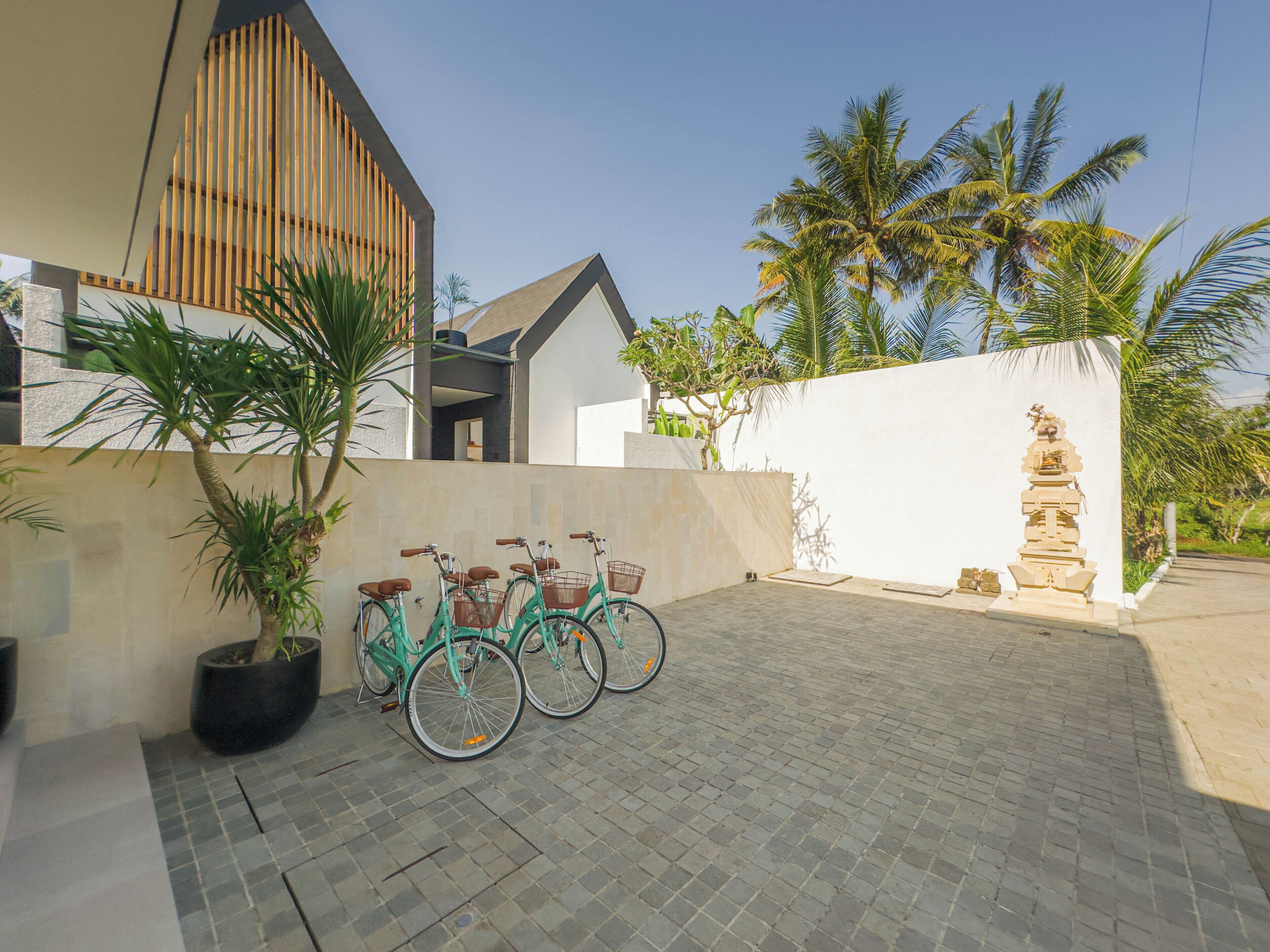 Una casa moderna con entrada pavimentada, un muro de listones de madera y una pared blanca con una estructura decorativa.
