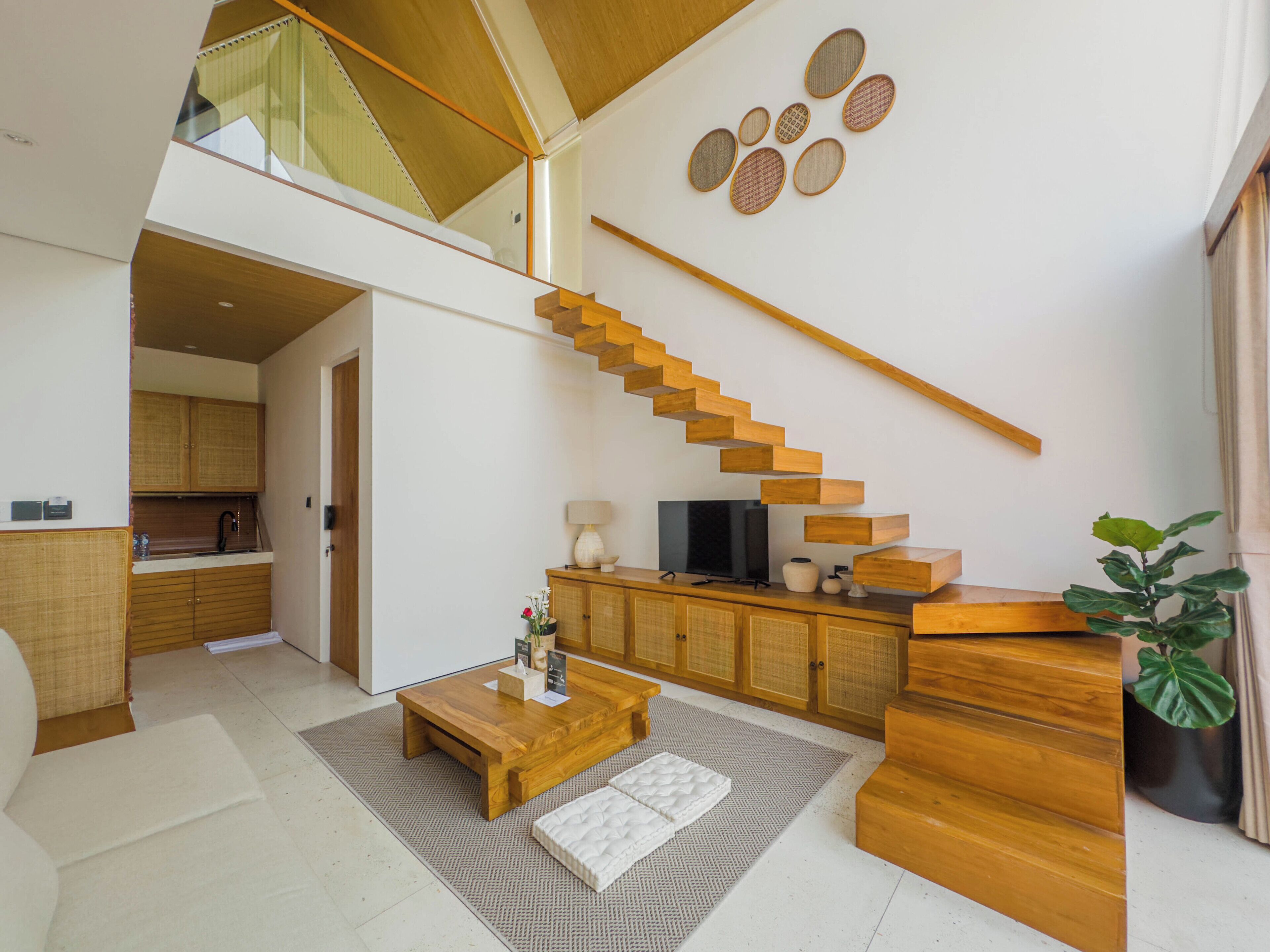 A modern interior with a wooden staircase, a flat-screen TV, and a dining area.