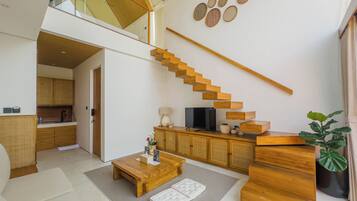 A modern interior with a wooden staircase, a flat-screen TV, and a dining area.