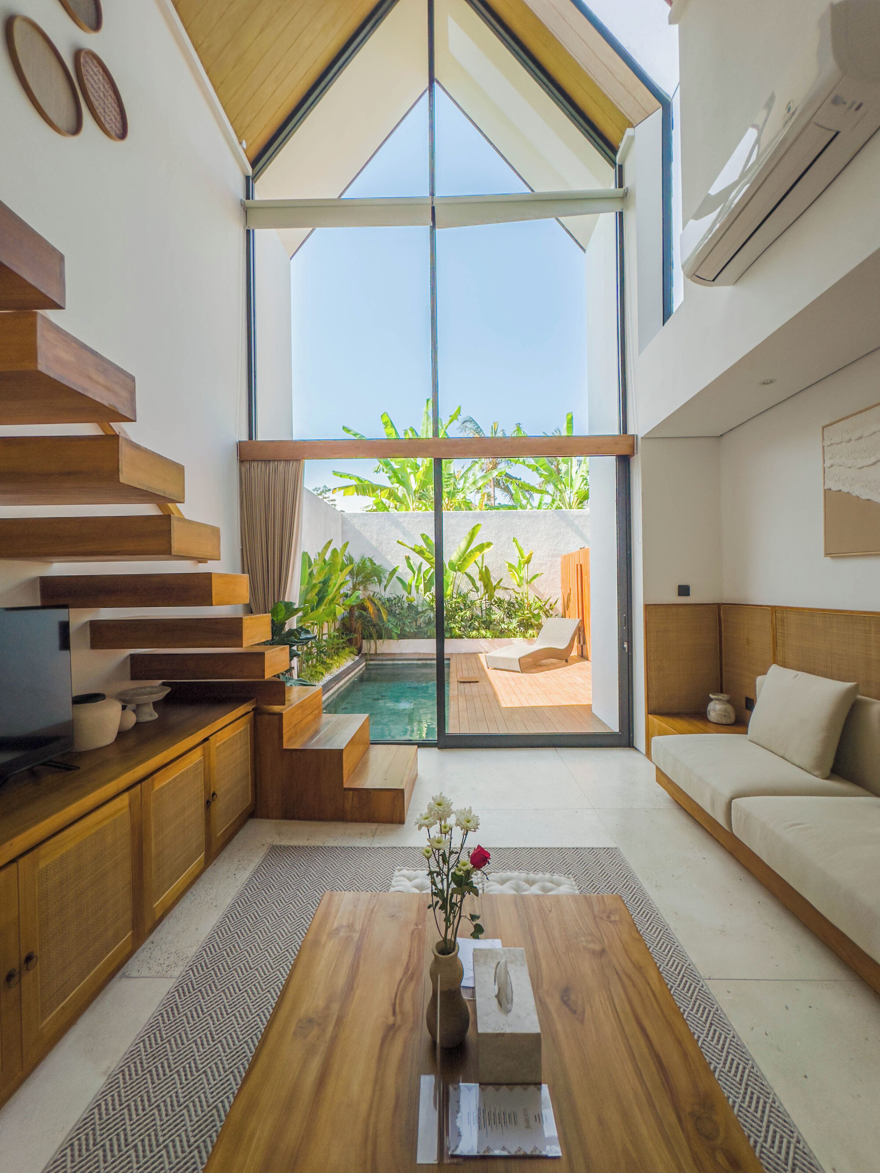 A modern interior with a wooden staircase, a pool, and a sofa.
