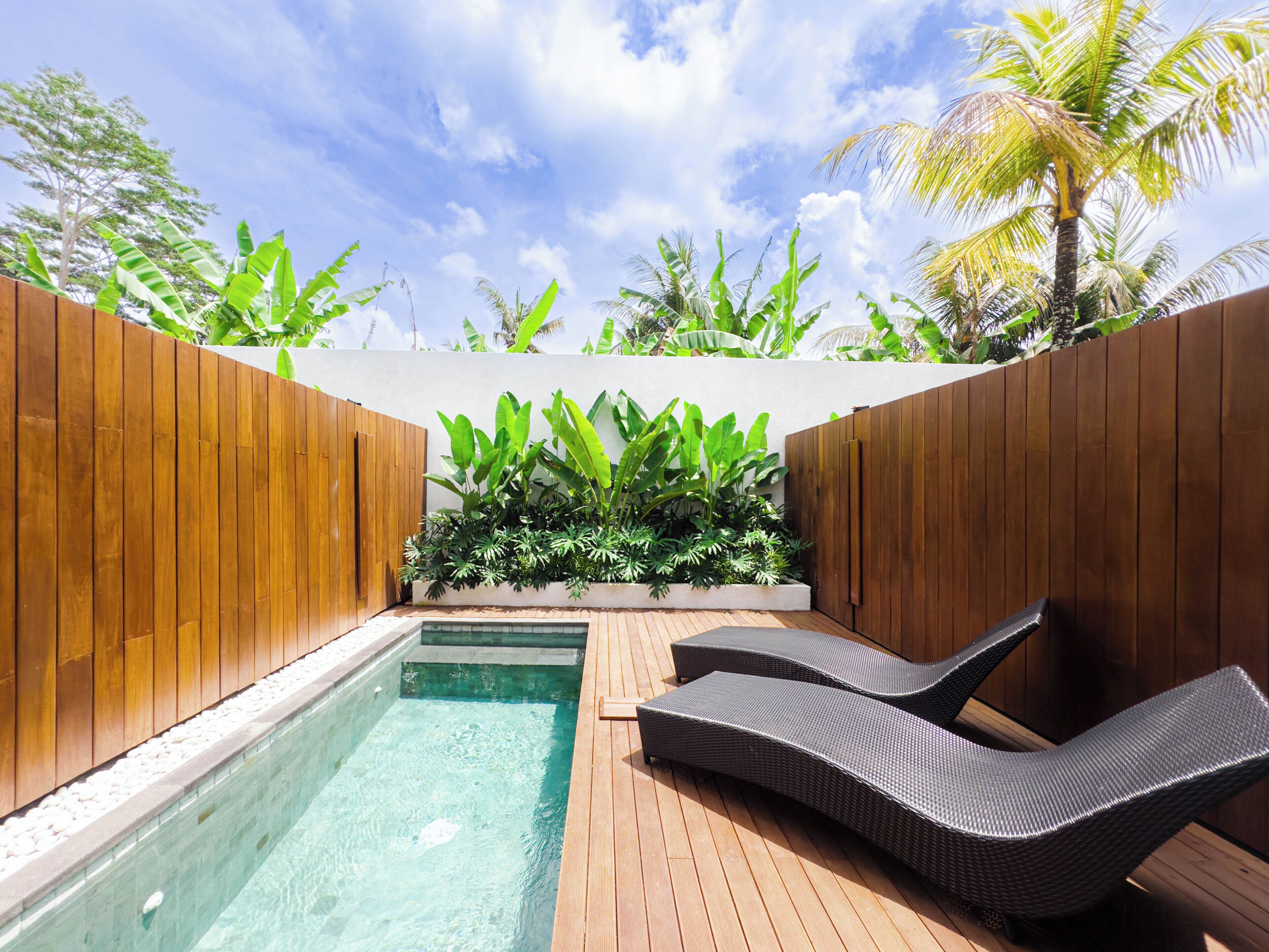 Une terrasse en bois avec une piscine et deux chaises longues.