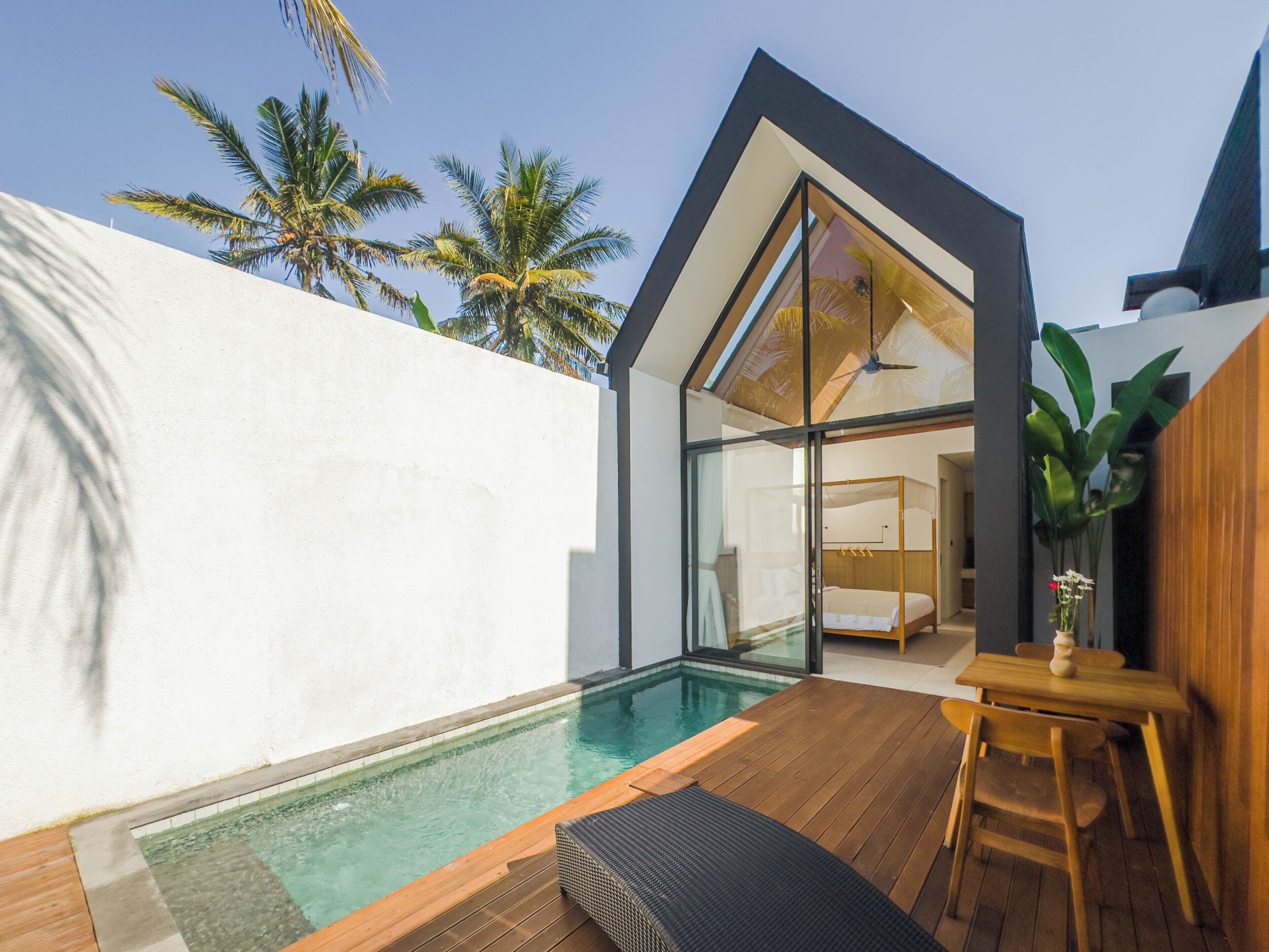 A modern house with a swimming pool, a wooden deck, and a bedroom with a bed and a ceiling fan.