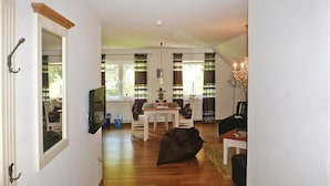 A hallway leading to a dining area with a table and chairs, a black bean bag, and a chandelier. - Ferienhof Landhaus Markus, Suderschwei (Stadland)