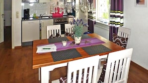 A dining area with a wooden table, white chairs, and a potted plant. - Ferienhof Landhaus Markus, Suderschwei (Stadland)