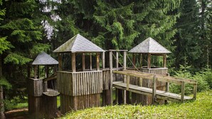 A wooden deck with three gazebos connected by a bridge, surrounded by dense forest. - Holiday Complex Erzgebirge Idyll, Breitenbrunn (Breitenbrunn/Erzgeb.)