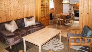 A cozy wooden interior with a sofa, a coffee table, and a dining area. - Holiday Complex Erzgebirge Idyll, Breitenbrunn (Breitenbrunn/Erzgeb.)