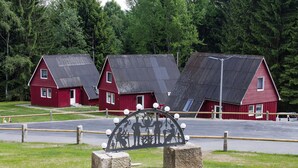 A row of red barns with metal roofs and a metal fence with a silhouette of people. - Holiday Complex Erzgebirge Idyll, Breitenbrunn (Breitenbrunn/Erzgeb.)
