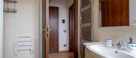 Un baño con ducha, lavamanos y espejo.